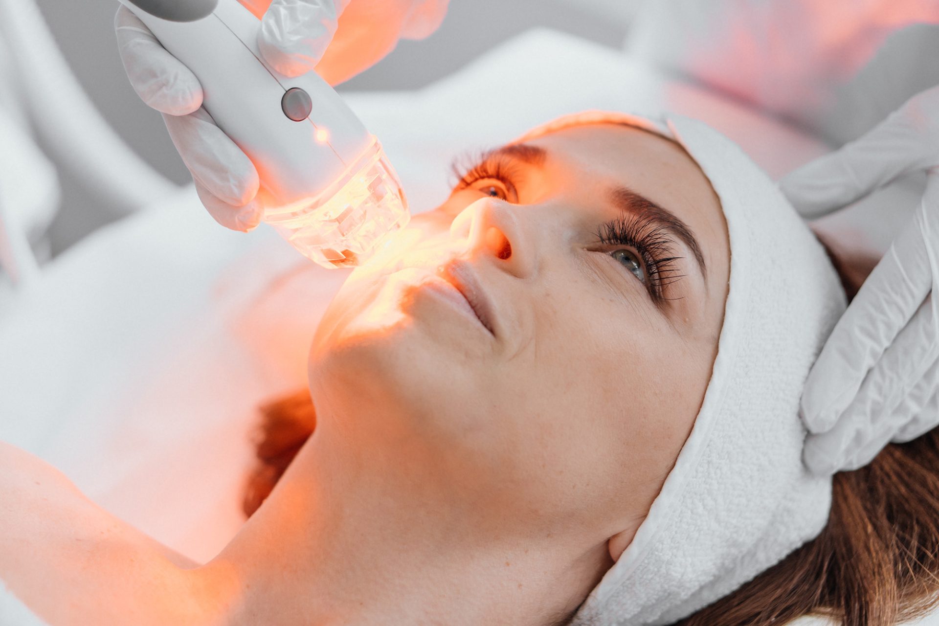 Red LED treatment. Woman doing facial skin therapy. Radiofrequency face lifting. Hardware antiaging procedure. RF lifting and vacuum massage. A cosmetologist performs a cosmetology procedure.