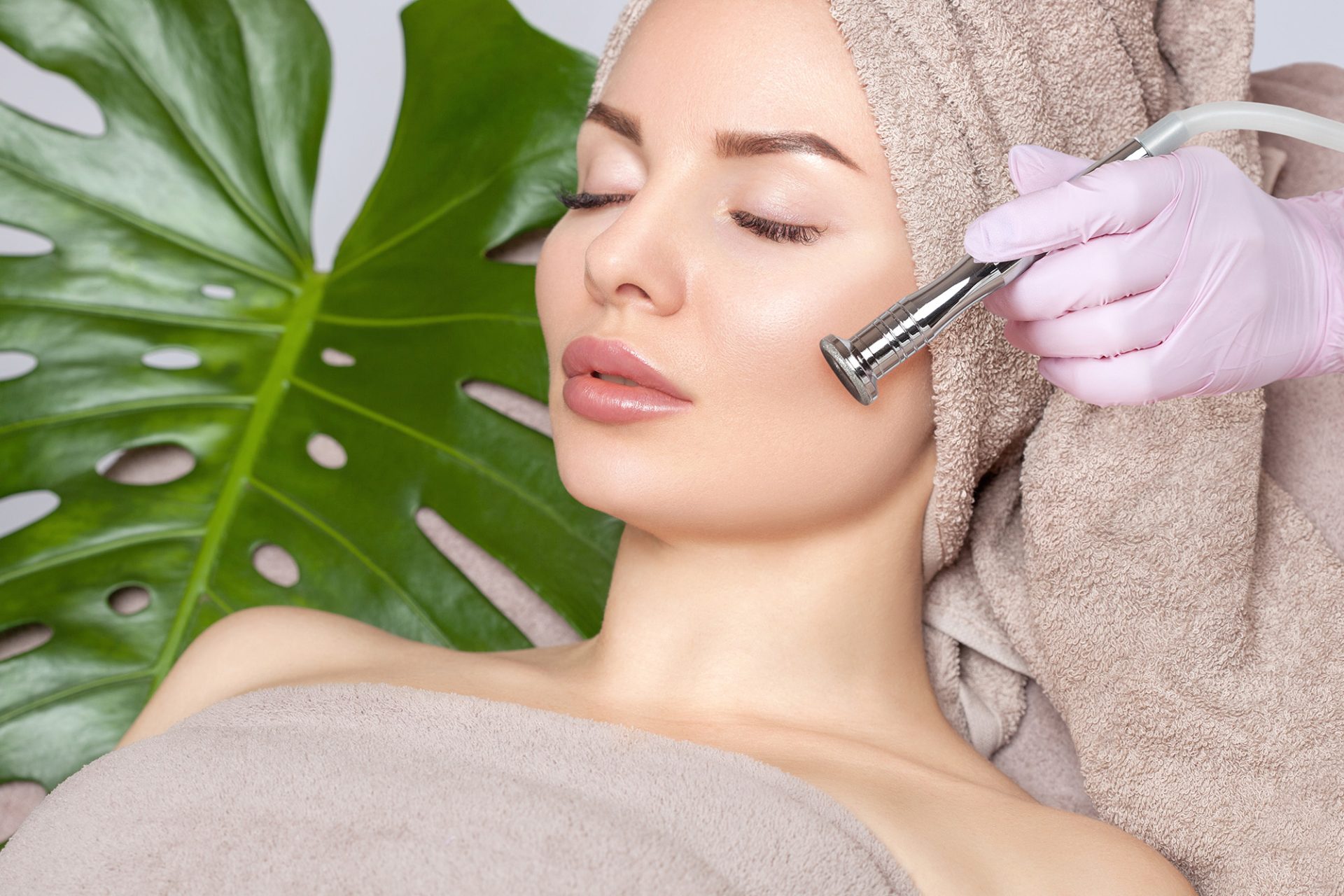 The cosmetologist makes the procedure of microdermabrasion on the face and collarbone of a beautiful woman in a beauty salon.Cosmetology and professional skin care.
